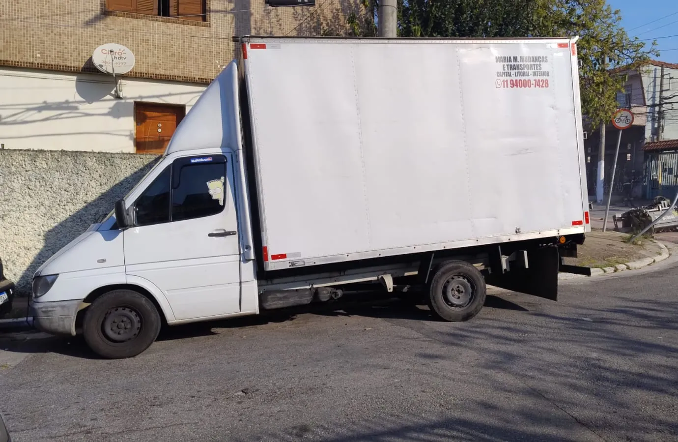 Caminhão baú da MMM visto de lado, com o telefone pintado na carroceria